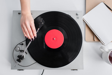 cropped view of woman playing vinyl record on vintage player