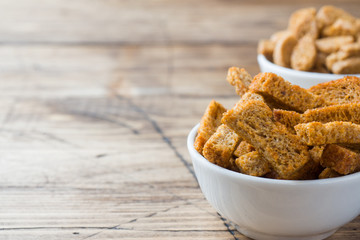 Croutons of grain bread with spices in the dishes. Wooden background. Copy space