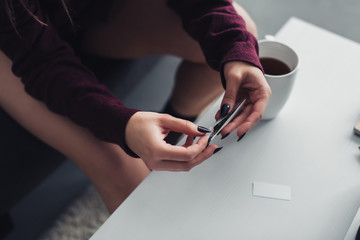cropped view of girl sitting and rolling marijuana joint at home