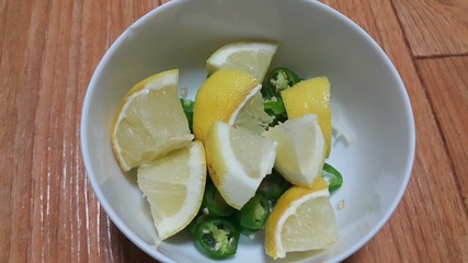 Top view of fresh lemon slices in a bowl over a wooden floor