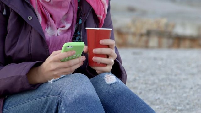 4K close up shot of a women holding a cup of hot dring in one hand and mobile in other