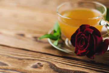 Glass cup with green tea and mint near red rose on sprig on old wooden table. Saint Valentine's Day concept