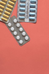 Blisters of different pills on pink background. Copy space for text