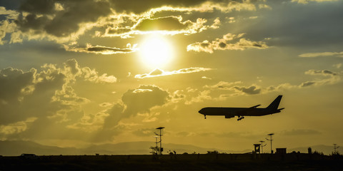 landing of the plane on the airfield against the bright sun and beautiful cloudy sky