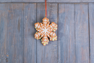 Gingerbread snowflakes cookies for Christmas hanging on wooden background.