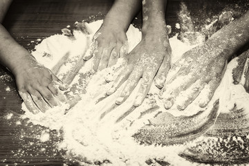 Kid's hands mixing flour on table