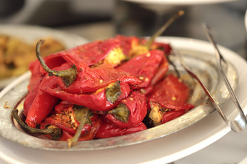 Hill of red grilled peppers on a white plate. Cut off shot, horizontal, nobody, close-up, side view, blurred. Healthy eating concept.