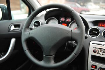 Modern luxury prestige car interior, dashboard, steering wheel. Black perforated leather interior.