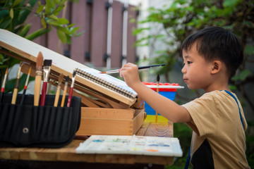 Young boy painting watercolor in the garden