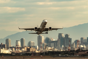 都市をバックに飛び立つ飛行機