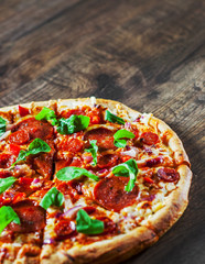 sliced Pepperoni Pizza with Mozzarella cheese, salami, chorizo, tomato sauce, pepper, Spices and Fresh arugula. Italian pizza on wooden table background