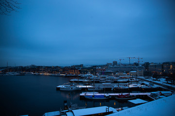 Fototapeta na wymiar Oslo Norway coast during winter with a large number of docked boats in the center of the city covered with snow