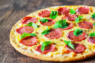 epperoni Pizza with Mozzarella cheese, salami, Tomato sauce, pepper, Spices and Fresh Basil. Italian pizza on wooden table background