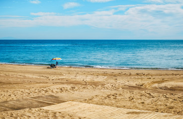 man relaxing under a beach colorful umbrella