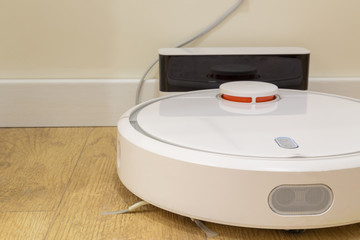 robot vacuum cleaner return to charging at dock in clean room floor. Extreme closeup background