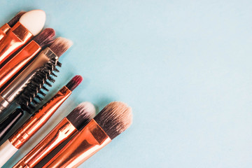 A set of beautiful different soft brushes for make-up from natural nap for beauty targeting and applying a tonal foundation in a stand and copy space on a blue background