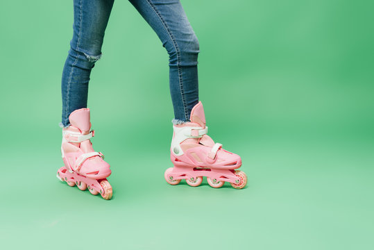 Partial View Of Child Wearing Denim And Pink Rollerblades Isolated On Green