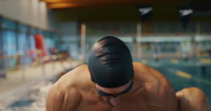 Professional swimmer with googles trains with effort and dedication to win the race by swimming in a freestyle pool. Concept of sport, swimming pool, competition, fitness.