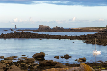 Porspoder, France. Rocky landscape in the coast of Brittany (Bretagne) at dawn on a beautiful summer day, with a boat and a lighthouse