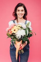 smiling woman holding flower bouquet isolated on pink