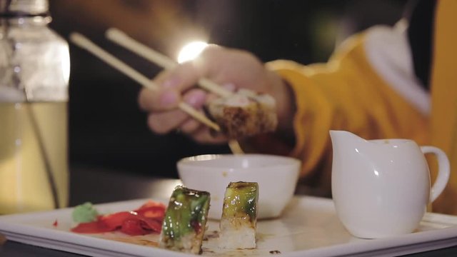 Girl eating sushi set with chopsticks on Asian restaurant, close up