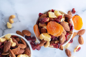 healthy snack: mixed nuts and dried fruits in wooden bowl on white background, almond, pineapple, cranberry, papaya, apple, strawberry, cherry, apricot, casshew. - Image