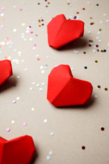 Red paper hearts and party confetti on gray background. Top view. Valentine's Day pattern. Symbol of love. Copy space