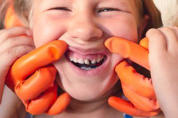 The doctor is trying to see the mouth of a little girl with an orthodontic appliance and crooked...