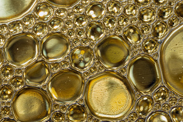 Abstract background of gold colored oil drops on water