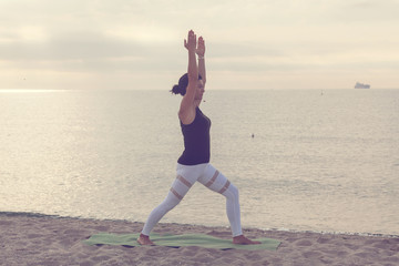 Fototapeta na wymiar Woman practicing yoga on the beach. Outdoors sports. Healthy living.
