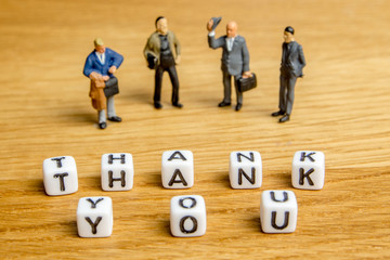 little miniature figurines with little dices forming word thank you as a part of team meeting...
