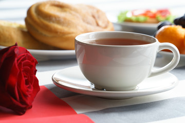 Romantic still life with a cup of tea and bright red holiday attributes.