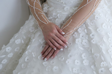 Morning of the bride. Beautiful hands of the bride with nail arts on the dress. 