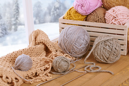 Woolen yarn and fabric on the window sill. Beautiful view outside the window - winter scenery and snow.