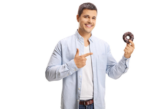 Smiling young man pointing to a donut in his hand