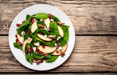 spinach salad, apple, pomegranate, cheese, walnut salad on wooden steel
