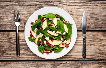 spinach salad, apple, pomegranate, cheese, walnut salad on wooden steel