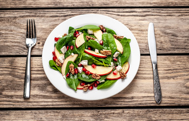spinach salad, apple, pomegranate, cheese, walnut salad on wooden steel
