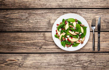 spinach salad, apple, pomegranate, cheese, walnut salad on wooden steel