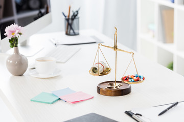 justice scales with money and drugs on table in business office