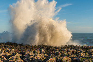 Fototapeta na wymiar Big waves breaking against the rocky Portuguese coast in Cascais, near Boca do Inferno a popular tourist attraction in Portugal. Dramatic seascape.