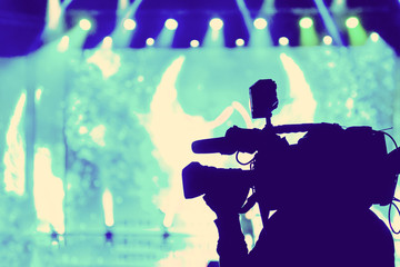 Professional Video camera operator working with his equipment, blue background