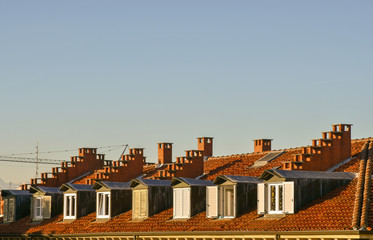 Close-up of a rooftop with dormer windows, chimney pots and clear sky background, Turin, Piedmont, Italy