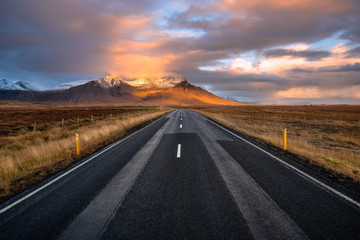 Scenic Road Through Grassy Fields to Snow-Capped Mountains in Iceland at Sunset