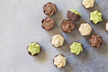 Yummy Assortment chocolate candies. Chocolate with vanilla, chocolate and pistachio cream on marble background. Top view flat lay background.