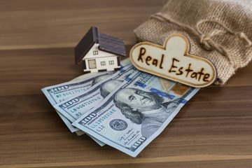 Real estate and mortgage investment. House ,dollar and wicker bag on the wooden background.