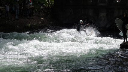 Young surfer on the river in Munich, Germany, surfing an artificial wave