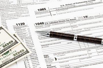 Obraz premium The tax forms with money and the pen. Tax Day concept