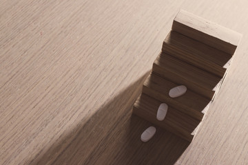 Pharmaceutical and medical expenditure concept with pills and wooden pieces