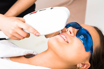 Naklejka premium Doctor beautician removes the hair on the patient's face with a laser apparatus